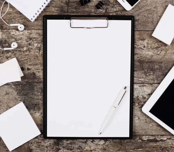 Hoja de papel blanco en blanco en una carpeta de clip rodeada de suministros de oficina , — Foto de Stock