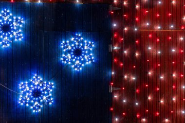 Ahırın ve ahır kapısının üzerinde kırmızı, beyaz ve mavi vatansever Noel ışıkları. Kar taneleri ve ABD renkleri.