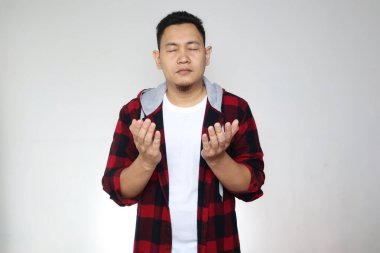 Asyalı Müslüman adam dua ediyor, elleri havada, gözleri kapalı. Ruhani kişi konsepti