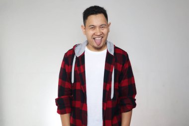 Komik Asyalı adam kameraya bakıyor ve dili ağzında gülümsüyor, aptalca bir jest.