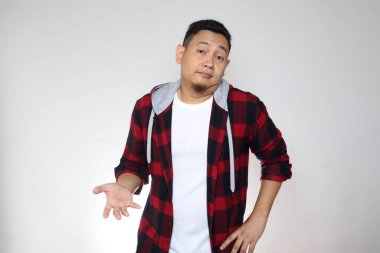  Asyalı adam, kafası karışmış bir ifadeyle omuz silkiyor. Gri üzerine bilgisiz bir ifade.