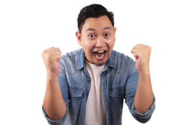 Başarılı genç Asyalı adam zafer kutlamalarında zafer jesti gösteriyor. Ellerini havaya kaldır ve mutlu bir yüz yap.