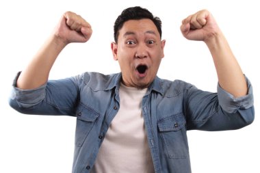 Başarılı genç Asyalı adam zafer kutlamalarında zafer jesti gösteriyor. Ellerini havaya kaldır ve mutlu bir yüz yap.