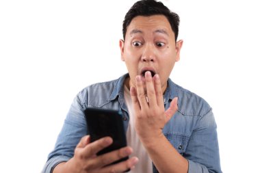 Çekici Asyalı genç adam telefonunda mesajlaşan mesajları okuyor, şaşırmış yüz ifadesi.