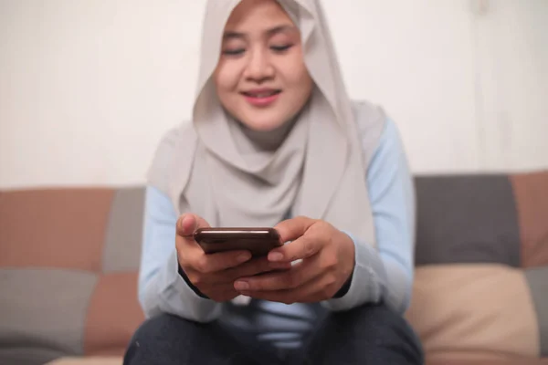 Asian Muslim Woman Sitting Sofa Home Using Phone Smiling Feeling — Stock Photo, Image