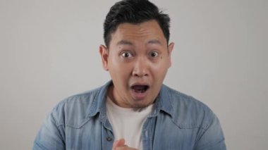 Asyalı komik bir gencin portresi, ağzı açık, şok olmuş veya şaşırmış bir ifade sergiliyor.