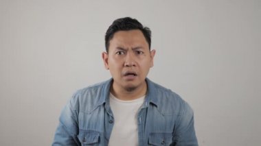 Asyalı komik bir gencin portresi, ağzı açık, şok olmuş veya şaşırmış bir ifade sergiliyor.