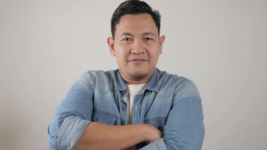 Mutlu, çekici, yakışıklı Asyalı adam, neşeli, kendine güvenen, kolları bağlı, dost canlısı bir hareket. 