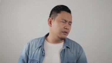 Asyalı adam üzgün ve pişmanlık dolu bir ifadeyle kameraya bakıyor, hayal kırıklığına uğramış bir jest.