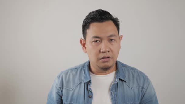 Asiatisk man tittar på kameran med sorg och ånger uttryck, besviken upprörd gest — Stockvideo