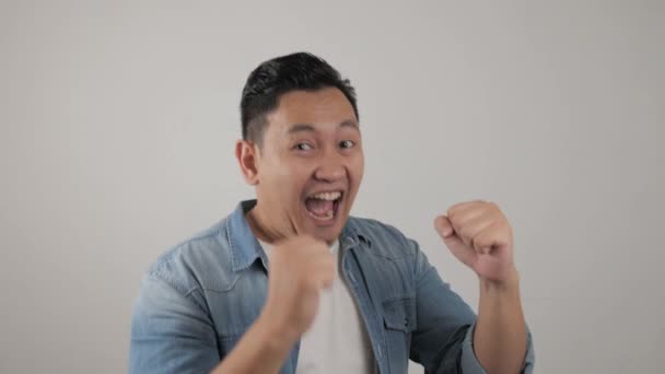 Hombre asiático sonriendo y bailando felizmente, alegre expresando celebrando buenas noticias victoria ganando éxito gesto — Vídeos de Stock