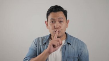 Sessiz olmak isteyen Asyalı bir gencin portresi.