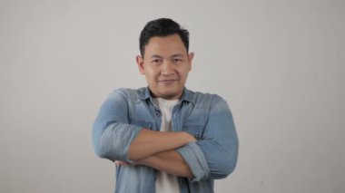 Mutlu, çekici, yakışıklı Asyalı adam, neşeli, kendine güvenen, kolları bağlı, dost canlısı bir hareket.