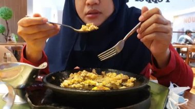 Samarinda, Endonezya, 27 Aralık 2020, alışveriş merkezinde öğle yemeği yiyen müslüman kadın, omlet pilavı ve körili ocağı seven kadın, yakın plan.