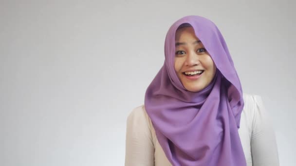 ヒジャーブを身に着けている美しいアジアのイスラム教徒の女性は 白の背景に何か良い 興奮ジェスチャーを参照してくださいに驚いて見えた — ストック動画