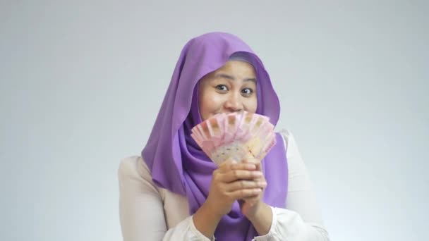 美しいインドネシアのイスラム教徒の女性は幸せそうに見えます 彼女のRupiaお金を見せながらカメラに笑顔 — ストック動画