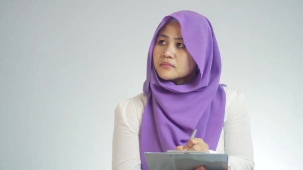 Красивая Азиатская Мусульманка Проводит Проверку Качества Смотрит Сторону Пишет Бумаге — стоковое видео