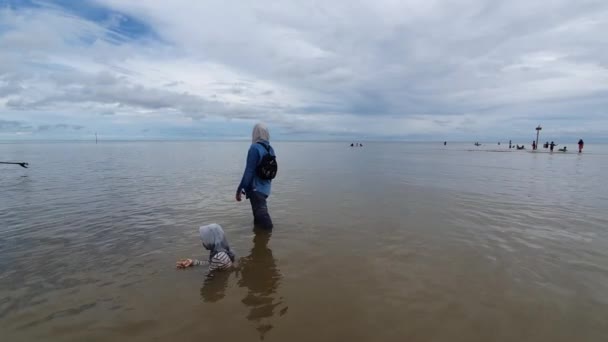 2021 인도네시아의 라마루 해변의 사람들은 물결을 즐기고 있으며 어머니는 딸에게 — 비디오