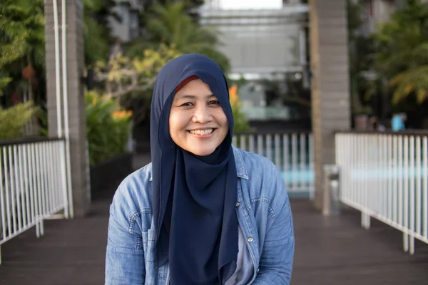 Szczęśliwy Azji Muzułmanin Kobieta Earing Hijab Uśmiechnięty Podczas Siedzenia Zewnątrz — Zdjęcie stockowe