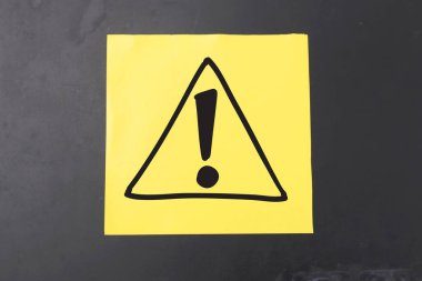 Koyu arkaplana karşı sarı kağıda çizilmiş tehlikeli işaret sembolü uyarısı 