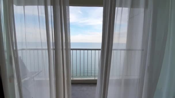 POV dolly ή drone shot από το εσωτερικό δωμάτιο του ξενοδοχείου, άνοιγμα κουρτίνα για να δείτε μπλε θέα στον ωκεανό, τον τουρισμό που ταξιδεύουν — Αρχείο Βίντεο