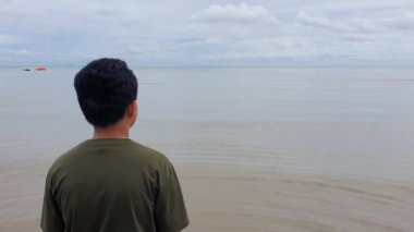 Sahilde yürüyen Asyalı çocuk, deniz kenarında yalnız bir çocuğun portresi.