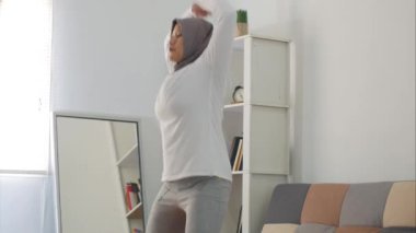 Asyalı müslüman kadın tesettür takıyor evde egzersiz yaparken dizüstü bilgisayarda video eğitimi, kapalı ev antrenmanı konsepti, yeni normal yaşam tarzında sağlıklı kalmak, zıplama krikoları