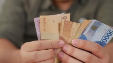 Uang Endonezya rupiası, el konsepti olarak nakit para sayan birine yaklaş.