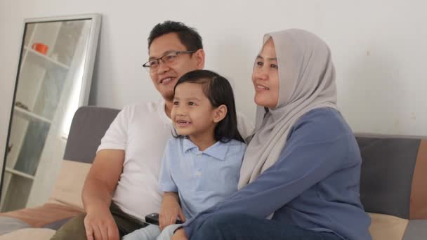 快乐的穆斯林家庭看电视 亚洲的父亲和母亲与女婴在家看电影度过了一段美好的时光 — 图库视频影像