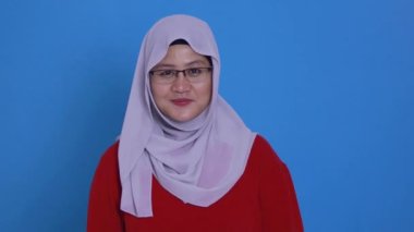 Asyalı Müslüman kadın tesettüre bürünmüş, gülümsüyor kolları bağlı, kendinden emin, başarılı bir kadın. 