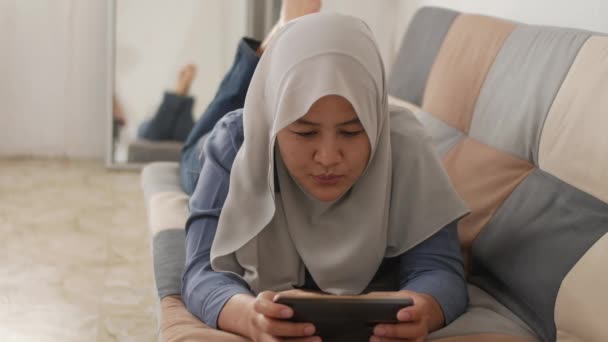 Vacker Asiatisk Muslimsk Kvinna Som Använder Telefon Medan Kopplar Soffan — Stockvideo