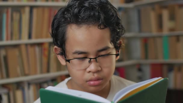 เด็กนักเรียนเอเชียฉลาดอ่านหนังสือในห้องสมุดแนวคิดการศึกษาเด็กเรียนรู้ที่บ้าน — วีดีโอสต็อก