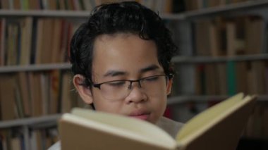 Genç Asyalı öğrenci portresi kitap okurken uykulu ve esniyordu, öğrenci sıkı çalışırken yorgundu.