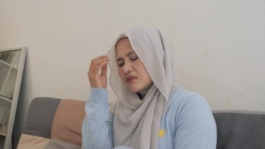 Üzgün Asyalı Müslüman kadın, tesettüre girmiş, pişman bir şekilde ağlıyor, elleri başının üstünde, gözleri kapalı, depresyonda. 