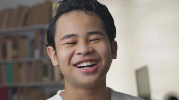 Портрет молодого азіатського студента, який дивиться на камеру і посміхається — стокове відео