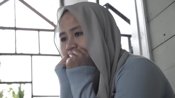 Smutna muzułmanka kontemplująca coś siedząc na zewnątrz swojego domu — Wideo stockowe