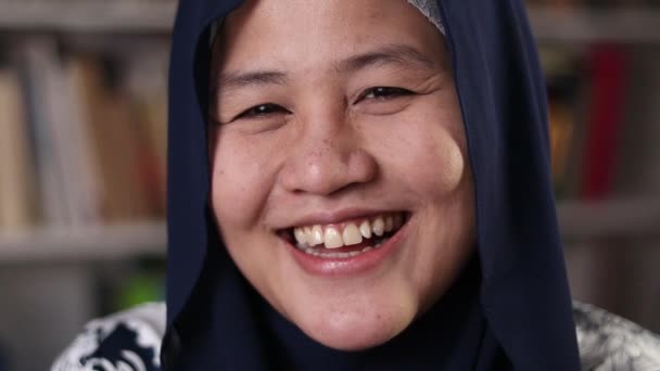 Felice donna musulmana asiatica che indossa hijab sorridente e ridente alla macchina fotografica, studentessa in biblioteca — Video Stock