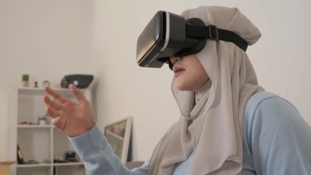 Mutlu genç Asyalı Müslüman kadın, tesettüre girmiş, VR gözlükleriyle oynuyor. — Stok video
