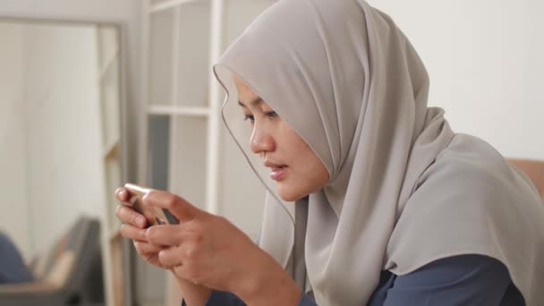 Mulher Muçulmana Asiática Bonita Usando Telefone Enquanto Relaxa Sofá Jogando — Vídeo de Stock