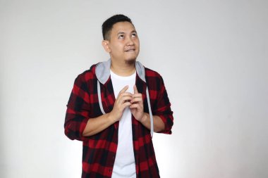 Komik Asyalı adam büyük bir umutla, gülümseyen bir ifadeyle, iyi bir şey beklerken yukarı bakıyor.