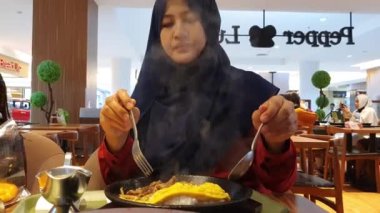 Samarinda, Endonezya, 27 Aralık 2020, alışveriş merkezinde öğle yemeği yiyen müslüman kadın, omlet pilavı ve körili ocağı seven kadın, yakın plan.