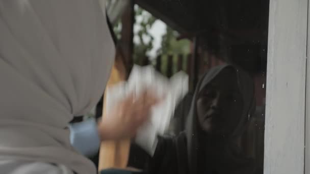 Muzułmanka czyszcząca szyby w oknach za pomocą wag i spray 'u, okno na zewnątrz — Wideo stockowe