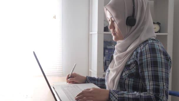 家庭でラップトップでテレビ会議をしているアジアのイスラム教徒の女性 オンライン学習や家庭の概念から働く — ストック動画