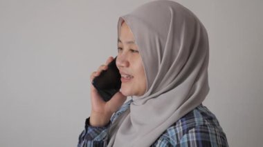 Mutlu Asyalı Müslüman kadın tesettürlü telefonda konuşuyor, iyi haberler iletişim konsepti, gülen yüz, kenar görüş