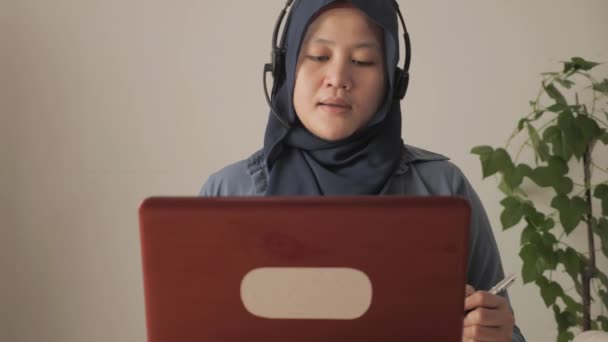 Ασιατική μουσουλμάνα γυναίκα που έχει τηλεδιάσκεψη βίντεο στο laptop της στο σπίτι, online μάθηση ή εργασία από το σπίτι έννοια — Αρχείο Βίντεο