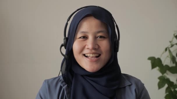 Krásná asijská muslimka používá sluchátka mluvící do kamery, POV, vysvětlující něco. Profesionální učitel mentor zákaznický servis podpora dělat on-line chat nebo video call koncept — Stock video