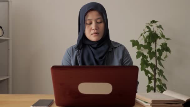 Asiatisk muslimsk kvinna bär hijab skriva på sin bärbara dator medan du läser bok, arbete hemifrån koncept. Tolka entreprenör eller högskolestudent lärande — Stockvideo