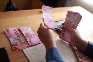 Kadın eli sayma Endonezya rupiası ve notlar alma, para yönetimi konsepti