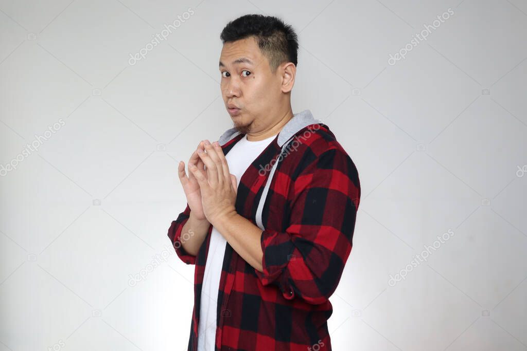 Portrait of Asian man looking to camera with embarrased worried hoping something gesture, shocked expression