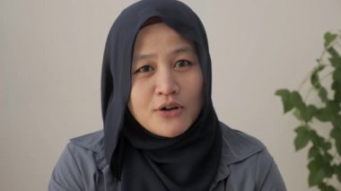 Mutlu Asyalı Müslüman kadın tesettüre giriyor, kameraya konuşuyor, İslami Arap kadın POV 'u webcam ile konuşuyor, görüntülü konferans görüşmesi yapıyor iş görüşmesi kaydı yapıyor, Webinar online sunumunu ofiste yapıyor. 